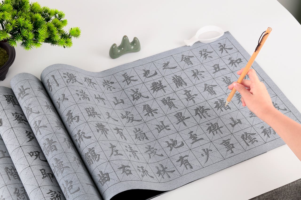 Close-up of a hand practicing Chinese calligraphy with a brush on a grid sheet. Ideal for artistic education themes.